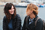Girl friends hanging out two beautiful women chatting having conversation by waterfront harbour 
