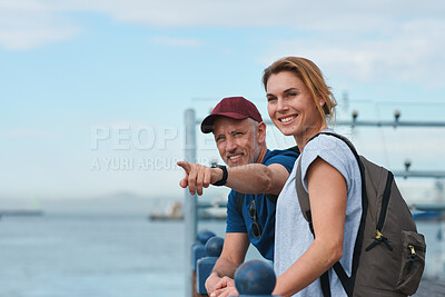 Buy stock photo Couple, travel and pointing in harbor for holiday, date and smile for summer sightseeing or bonding. Mature man, woman and tourist with trip, vacation and view together for honeymoon on waterfront