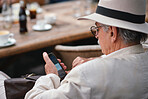Old man using smartphone in restaurant texting on mobile phone wearing white suit