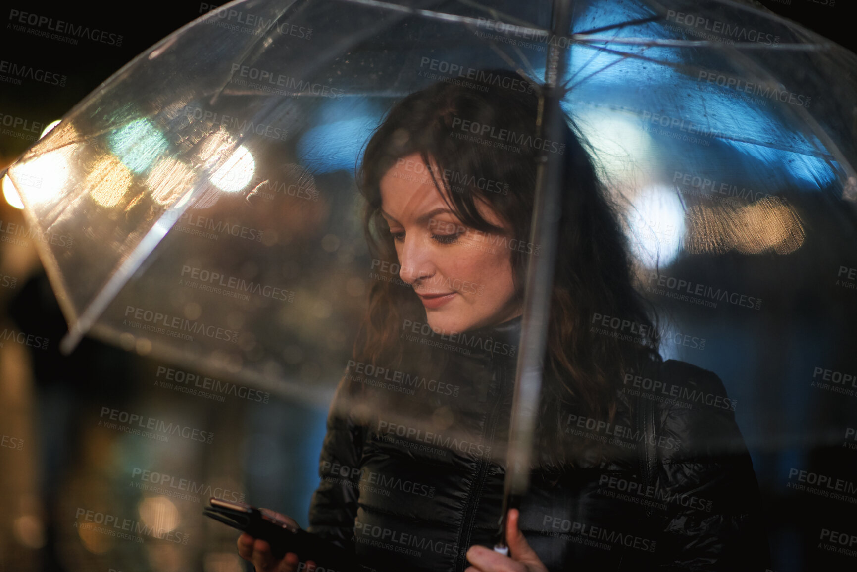 Buy stock photo Online, phone and woman with umbrella in city, communication and checking ride confirmation at night. Dark, outdoor and person with weather protection, bokeh and tracking taxi distance on mobile