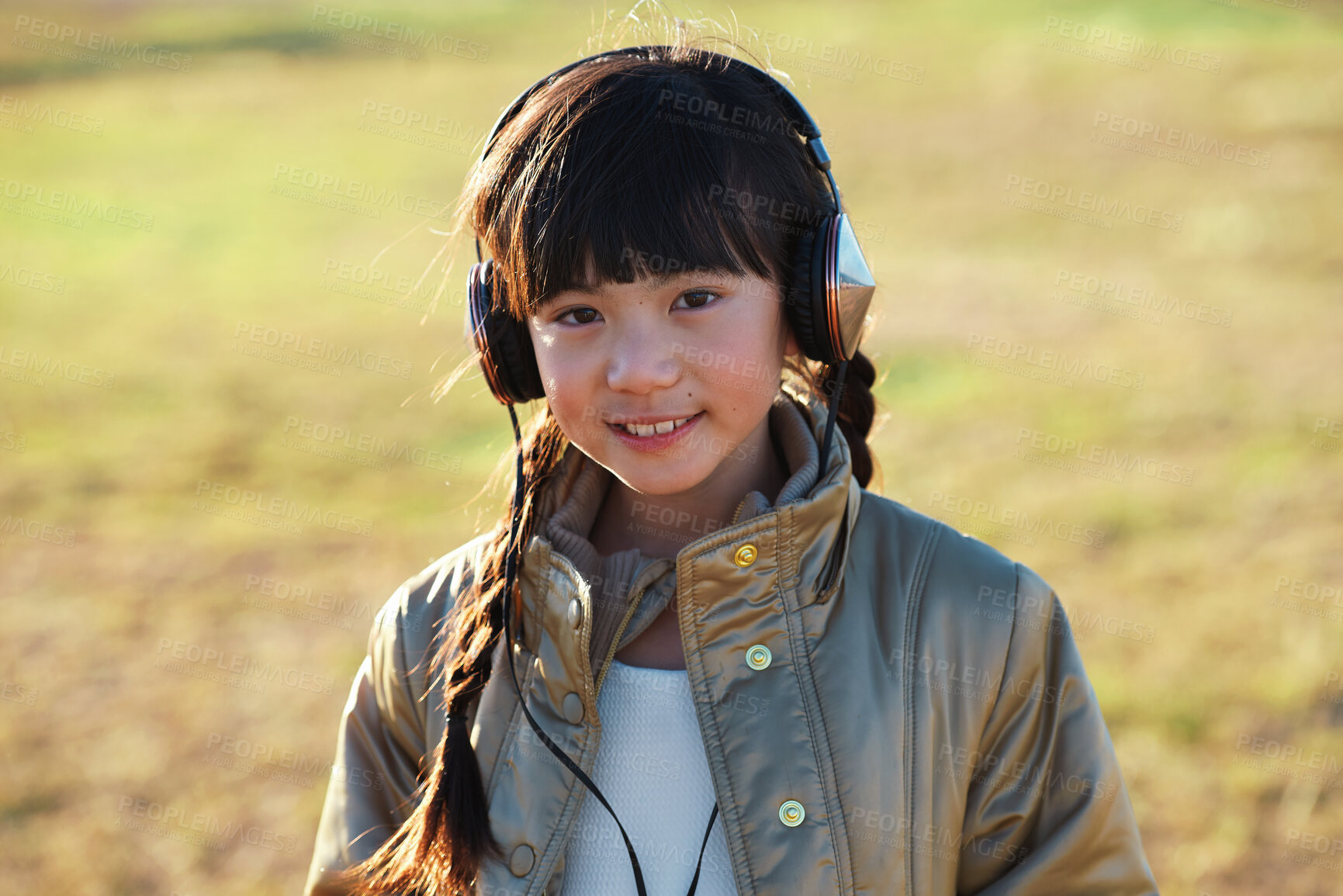 Buy stock photo Portrait, headphones and Asian kid in nature with music, smile and listening to radio song on vacation. Outdoor, adorable child and girl with audio, happy and streaming sound on holiday at park