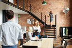 Team leader offering advice to intern in busy trendy office with business people