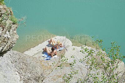 Buy stock photo Above, sun tan and woman friends on rocks by ocean for holiday, travel or vacation together. Bonding, break and tourist with girls at beach in bikini swimwear for getaway, relax or stress relief