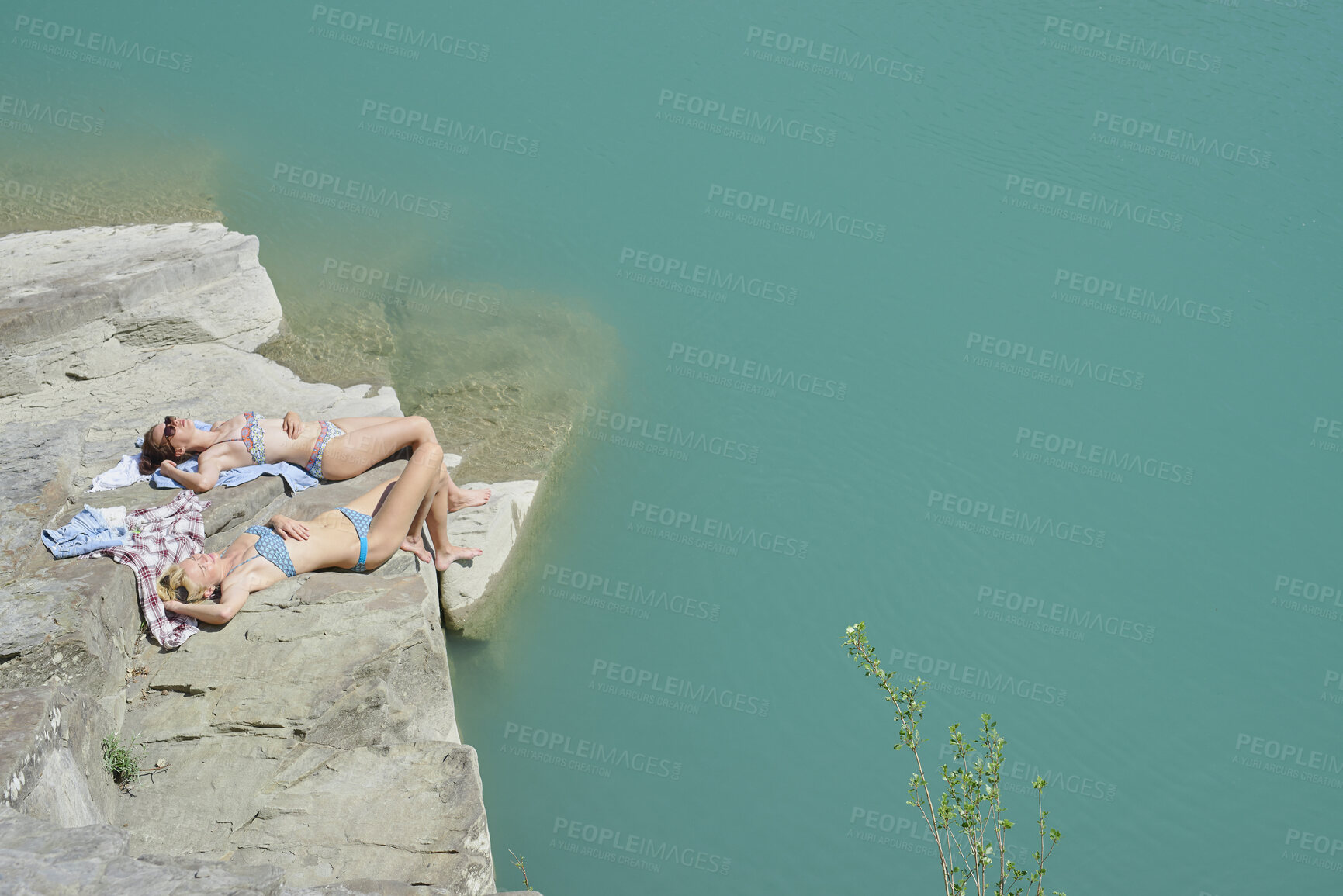 Buy stock photo Relax, ocean and girl friends on rock in summer on holiday, getaway or weekend trip with travel. Sunbathing, space and female people in bikini on cliff for break of swimming by sea water on vacation.