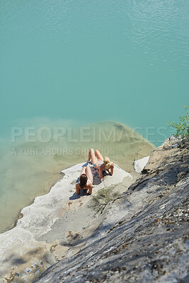Buy stock photo Relax, ocean and women on rock in summer on holiday, getaway or weekend trip with travel. Sunbathing, space and girl friends in bikini for swimming break in sea water on island vacation from above.