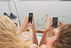 Beautiful girl friends on sailboat using smart phone technology for social meda in ocean on luxury lifestyle adventure travel vacation