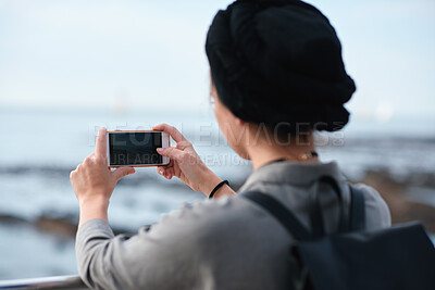 Buy stock photo Woman, travel or beach with phone camera for sightseeing memory, tourism or photography in nature. Back view, female person or tourist with mobile smartphone, app or screen on ocean coast for picture