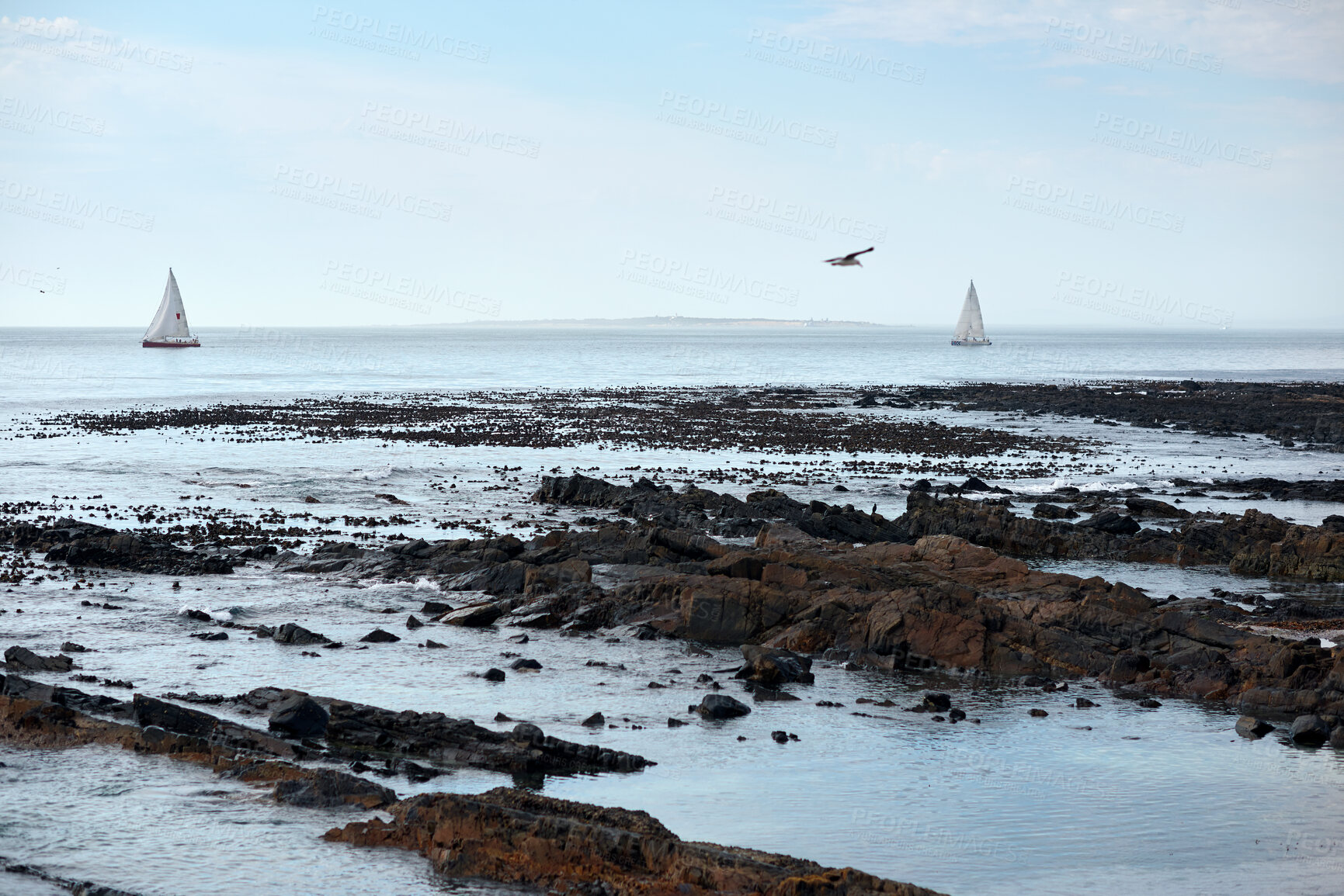 Buy stock photo Blue sky, seascape and yacht with view of ocean from seaside for holiday, travel or vacation. Clouds, horizon and rocks with boats on water for adventure cruise, getaway or voyage in morning