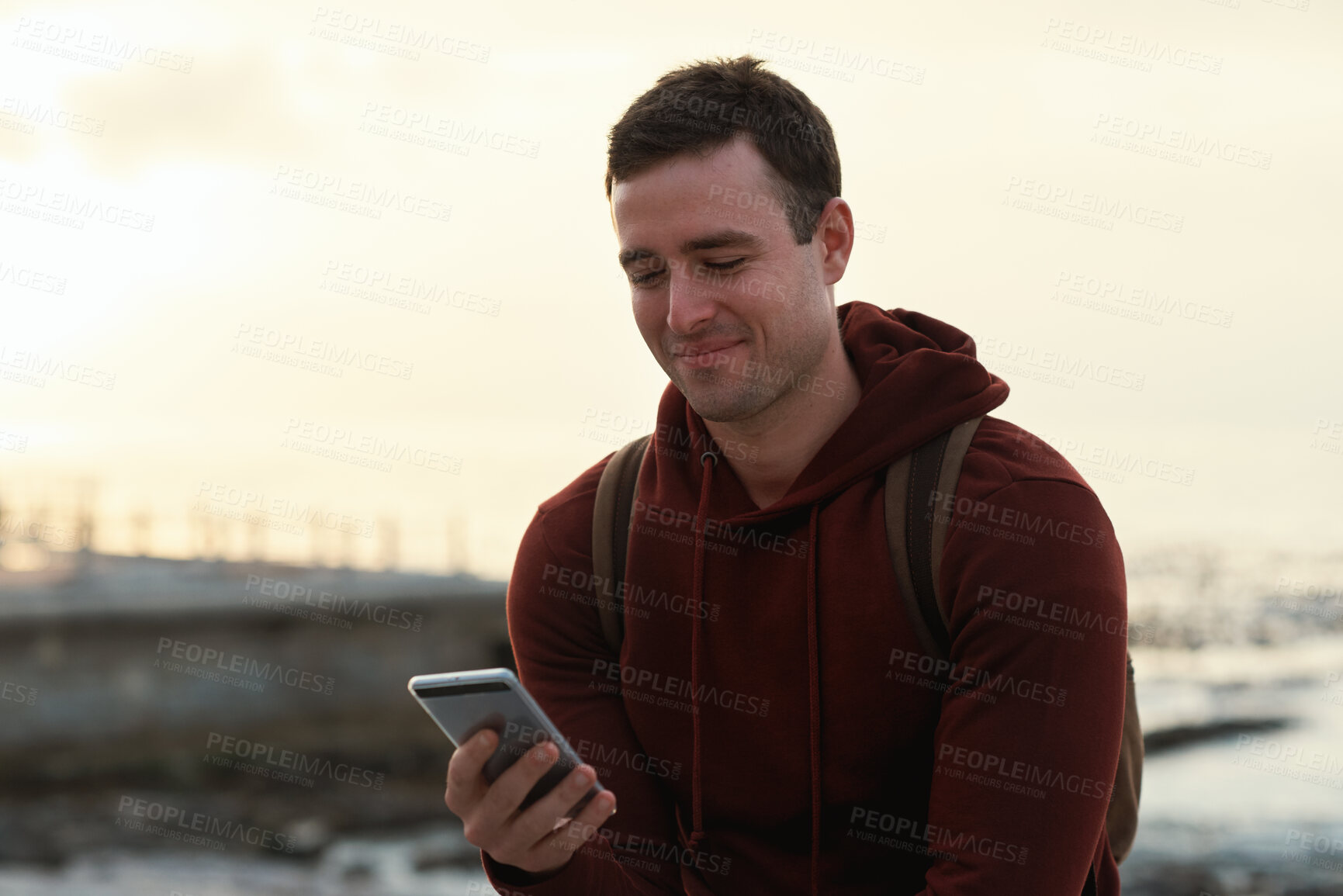 Buy stock photo Smile, holiday and man at beach with phone, social media and research for tourist guide. Space, male person and relax at seashore with mobile app, navigation and message notification on vacation trip