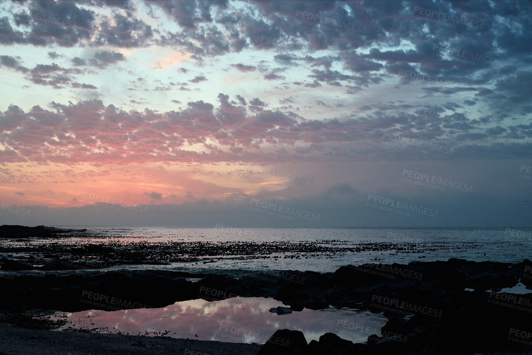 Buy stock photo Clouds, space and sunset with view of ocean from seaside for background or scenic wallpaper. Rocks, seascape and sky with water in colorful environment for calm dusk, nightfall or twilight scenery