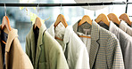 Rail, hanger and jacket in store with choice, decision and shopping for retail therapy with fabric quality. Fashion, design and blazer on rack in boutique with discount, deal or sale in mall.