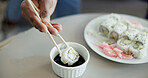 Hand, chopstick or sushi in home for dinner, Japanese cuisine or roll selection in living room. Hungry person, rice meal or soy sauce in dish to enhance flavour, seafood catering or platter in house