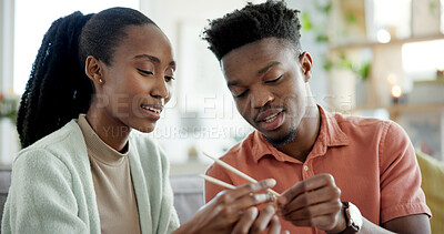Buy stock photo Couple, teaching and helping at house with chopsticks, technique and assistance for new skill. Smile, black people and learning with sticks for dining etiquette, guidance and bonding for tradition
