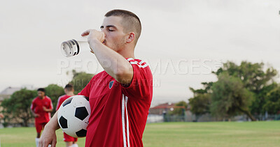 Buy stock photo Ball, drinking water and soccer with man outdoor on grass pitch for fitness or hydration. Bottle, space and sports with thirsty football player on field for competition, game or match practice