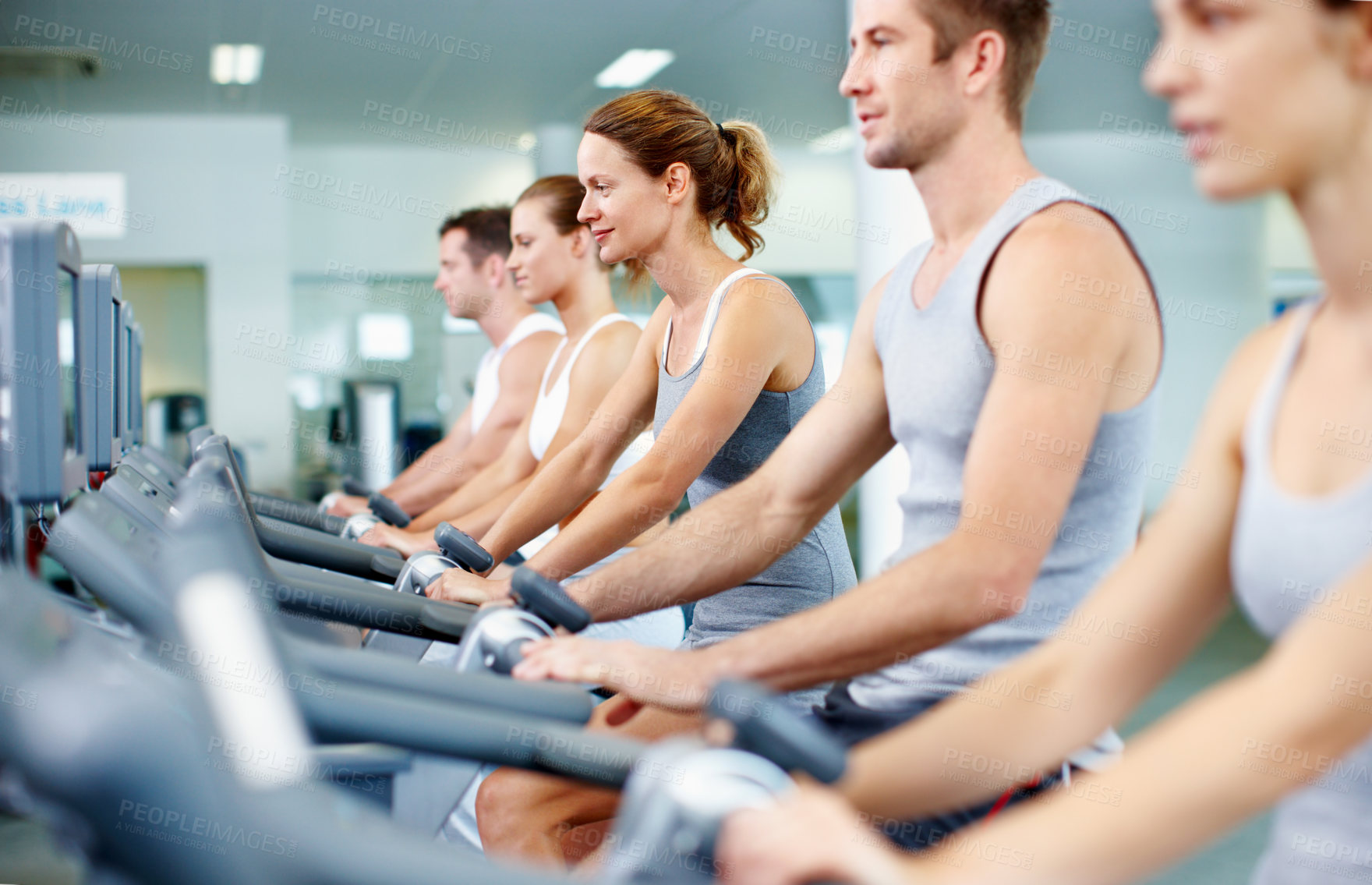Buy stock photo Shot of young men and women cycling in a gym