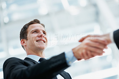 Buy stock photo Happy, businessman and shaking hands with client in office, agreement and investment deal in meeting. Business people, low angle and handshake with investor, smile or partnership for financial growth