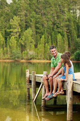 Buy stock photo Happy, father or relax with children at lake, conversation or bonding together on holiday. Smile, or and talking on pier with kids, family connection and weekend break on vacation trip in countryside