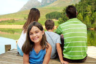 Buy stock photo Family, vacation and happy kid on lake dock, relax and portrait outdoor for summer travel. Girl, child and break at pier on holiday, countryside tourism and chill with parents by water in nature