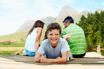 Buy stock photo Family, vacation and happy teen on lake dock, relax and chill outdoor for summer travel. Boy, portrait and weekend break at pier on holiday with smile, countryside tourism and parents in nature