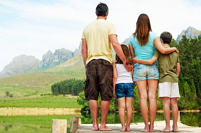 Buy stock photo Back, family and hug outdoor in countryside for summer holiday, vacation and together by lake. Mountains, pier and space by man, woman and children in nature to relax, bonding or connection with view