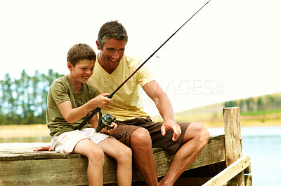 Buy stock photo Dad, kid and fishing at lake pier on vacation together, teaching and pointing to show spot for help. Parent, boy and rod by water outdoor for relax, learning and bonding with happiness on holiday