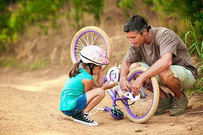 Buy stock photo Father, fixing and bicycle in nature with child, safety check and repair pedal for cycling. Man, helping or daughter outdoor with bike issues, mechanical skills and maintenance inspection for bonding