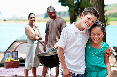 Buy stock photo Camping, kids and hug at barbecue outdoor with family picnic by lake, care or portrait together. Happy siblings, embrace and children by tent for bbq, love and connection with parents on vacation