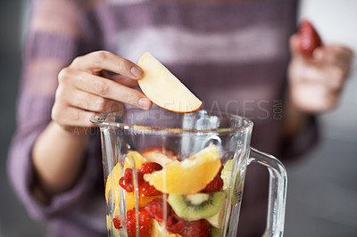 Buy stock photo A closeup cropped shot of a woman's hand putting sliced fruits into a blender