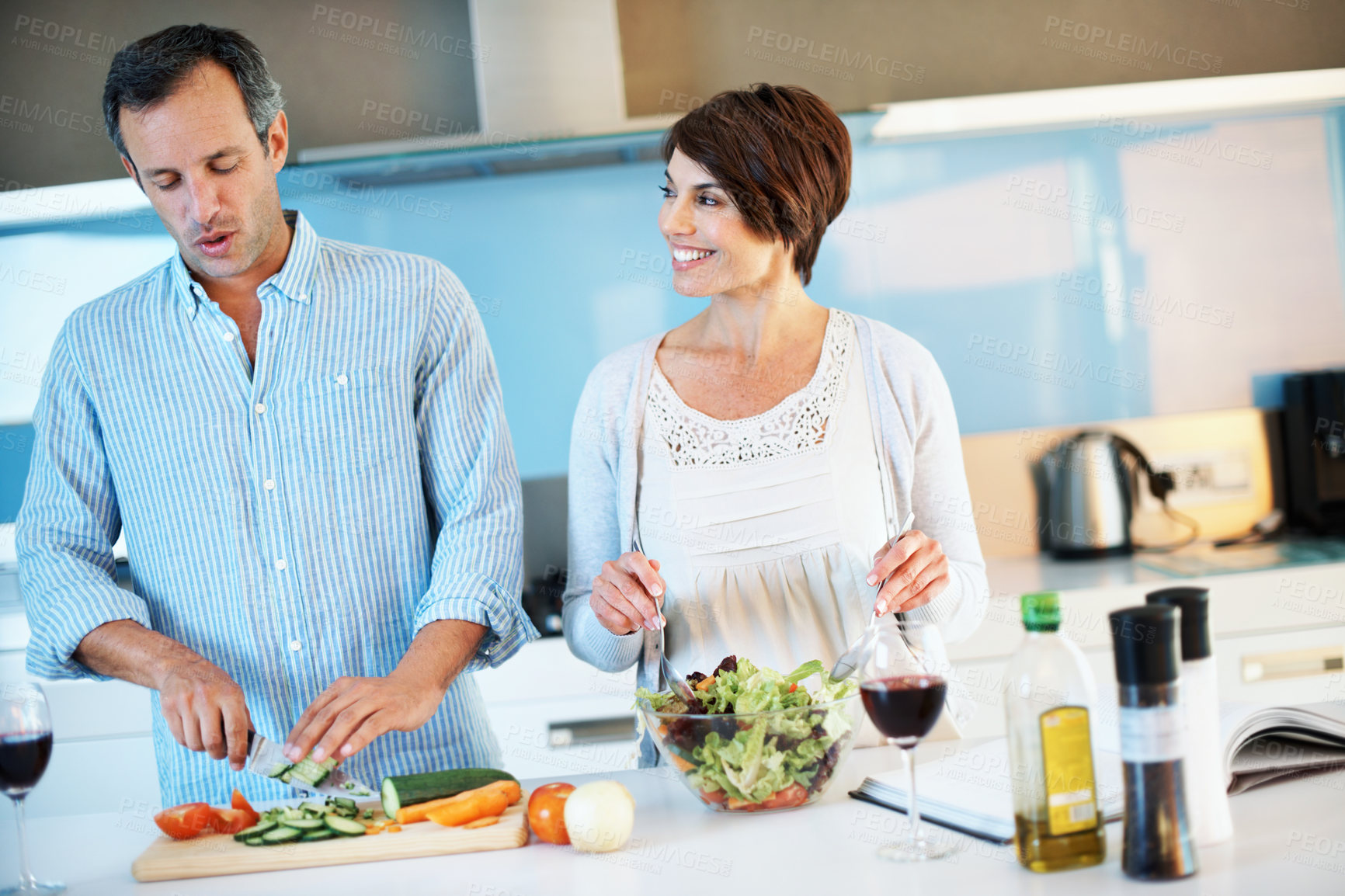 Buy stock photo Help, happy couple and cooking with vegetables in home to mix salad, organic food and wine. Mature man, woman and meal prep at kitchen, slice cucumber and vegetarian diet for nutrition with love