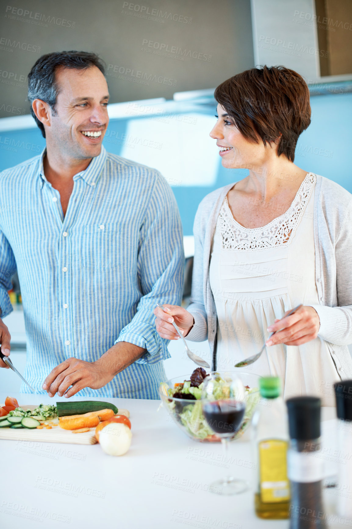 Buy stock photo Love, happy couple and cooking with vegetables in kitchen to mix salad, healthy food and wine. Mature man, woman and meal prep at home, cut cucumber and vegetarian diet for nutrition with smile