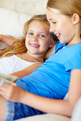 Buy stock photo Kids, home and reading book on sofa with smile, love and care for sibling or sister in lounge. Girls, children or happy family together for storytelling and learning, development or portrait on couch