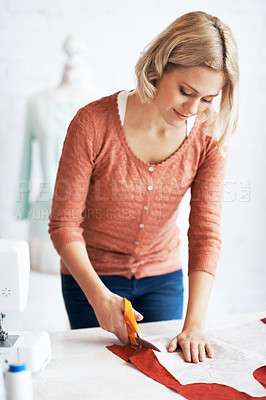 Buy stock photo A beautiful young tailor cutting material for a garment 