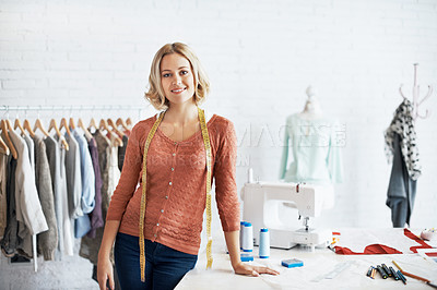 Buy stock photo Portrait of a fashion designer standing with tape measure around her neck and leaning on her work desk