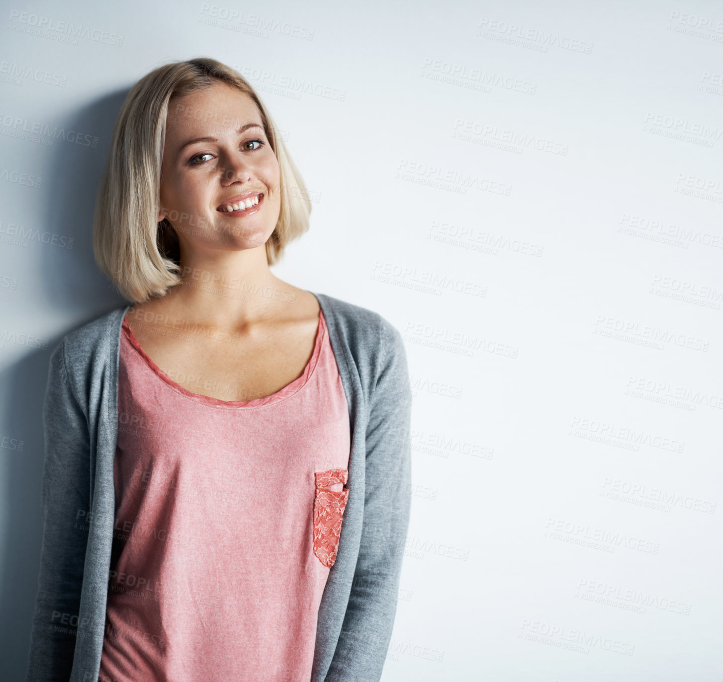 Buy stock photo Portrait of a pretty young blonde woman leaning against a white wall