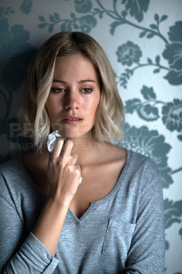 Buy stock photo A pretty blonde girl looking away while crying and holding a tissue