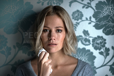Buy stock photo Portrait of a pretty young blonde woman crying while holding a tissue