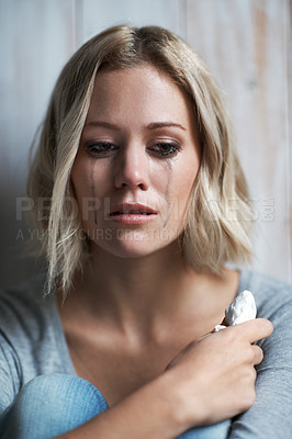 Buy stock photo A pretty young blonde woman looking down while she is crying