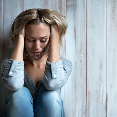 Buy stock photo A young woman looking down while tears run down her face