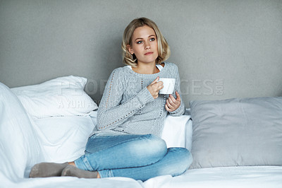 Buy stock photo A pretty young blonde woman sitting at home and enjoying a cup of coffee