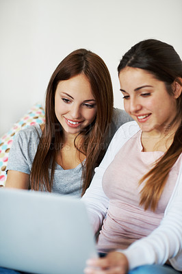 Buy stock photo Two teenage girls sharing a notebook while sitting on the sofa at home