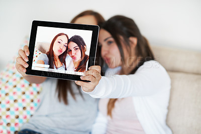 Buy stock photo Two teenage girls taking a picture of themselves on their tablet at home