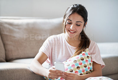 Buy stock photo A gorgeous teenage girl texting her friend while sitting on the living room floor