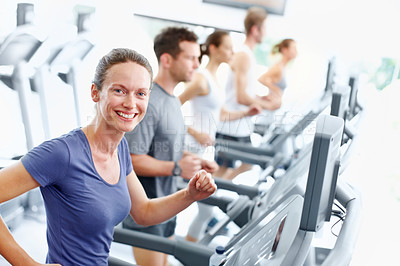 Buy stock photo Positive young woman running on a treadmill at the gym