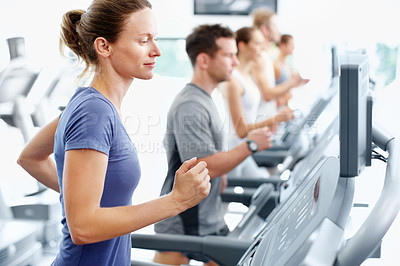 Buy stock photo Young woman running on a treadmill at the gym