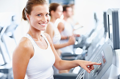Buy stock photo Smiling woman selecting a speed option on a treadmill at the gym