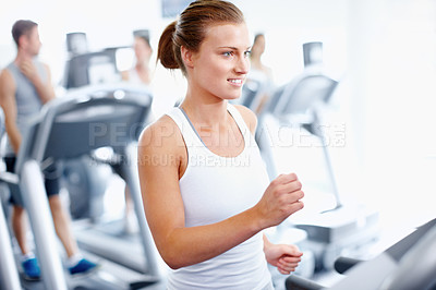 Buy stock photo Young woman jogging on a treadmill at the gym