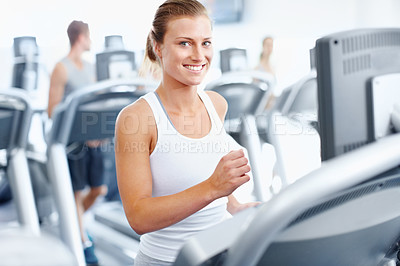 Buy stock photo Young woman jogging on a treadmill at the gym with a smile