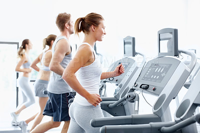 Buy stock photo Line of fit young people using equipment at the gym