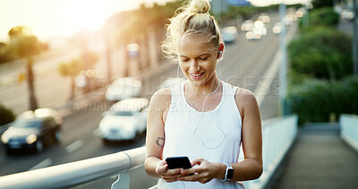 Buy stock photo Fitness, phone and woman with earphones on bridge, texting and listening to music with subscription. Happy, athlete and person with chat on mobile, wellness and streaming audio with tech in city