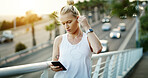 Fitness, online and woman with earphones on bridge, texting and listening to music with subscription. Serious, athlete and person with phone for chat, wellness and streaming audio with tech in city